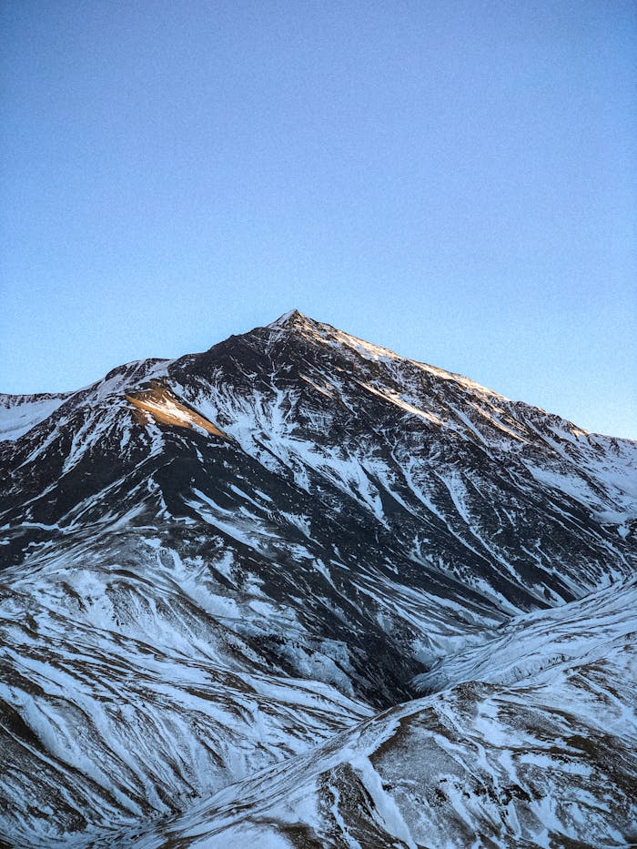 A breathtaking view of a snow-capped mountain under a clear blue sky, showcasing nature's beauty.