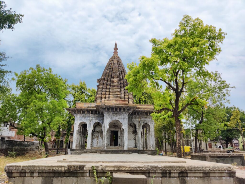 A historic temple surrounded by vibrant green trees under a bright, clear sky, offering a serene view.