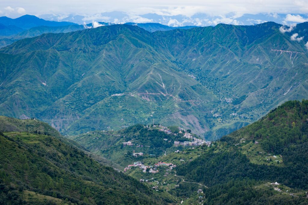 A breathtaking aerial view of a green mountainous landscape with a village nestled in the valley.
