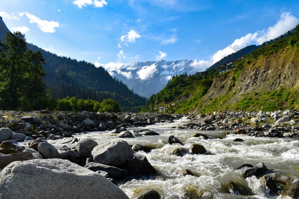 Flowing river through rocks with mountain backdrop in Manali, India