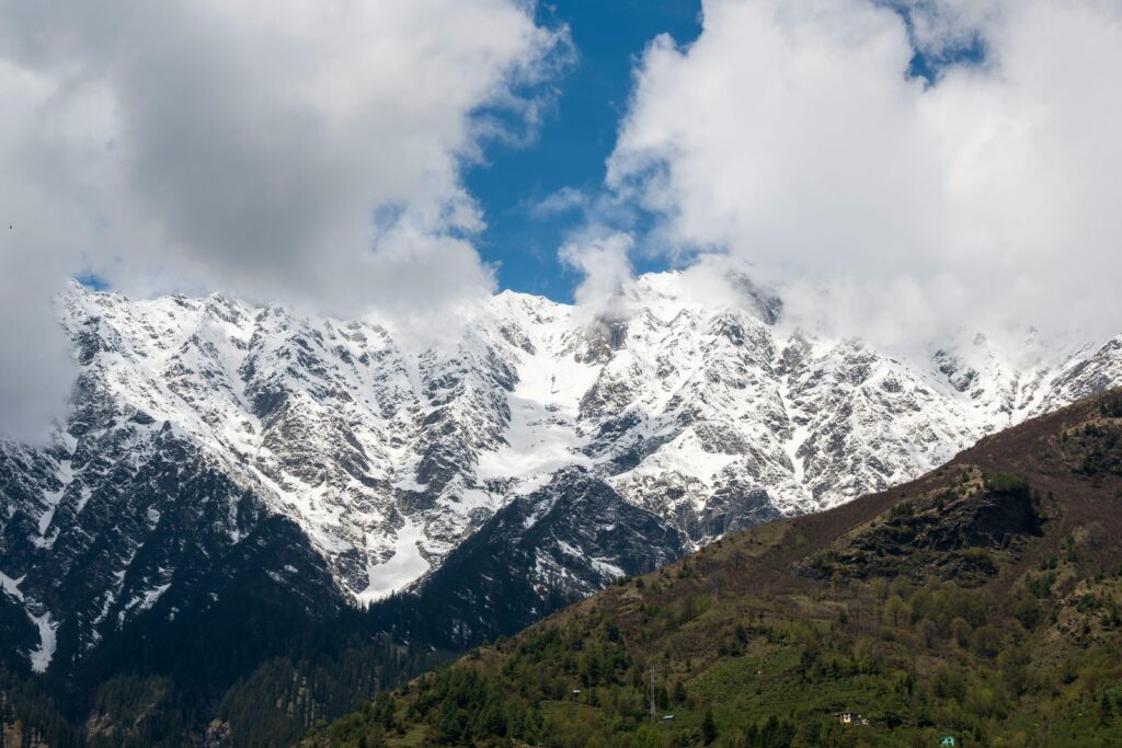 Breathtaking view of snowcapped peaks and lush green valleys in Kullu, HP, India.