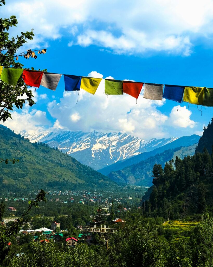Charming view of Manali village with Himalayan mountains and colorful prayer flags in summer.