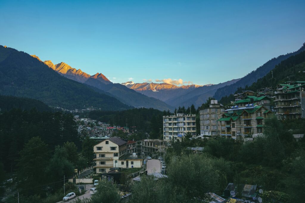 Breathtaking view of Manali town with the Himalayan mountains glowing at sunset in Himachal Pradesh, India.