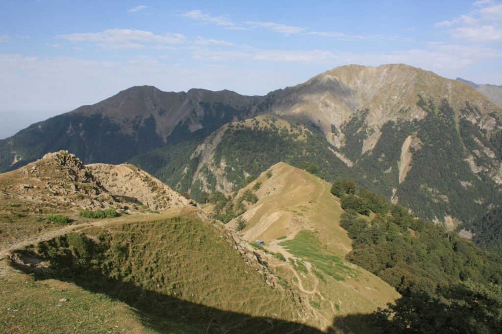 Explore the stunning mountainous landscape with lush greenery and clear skies, perfect for adventure enthusiasts.