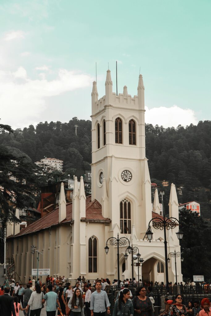 Gothic architecture of Christ Church in Shimla with a bustling crowd and scenic hills in the background.